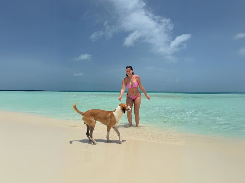 Turista en bikini disfrutando del sol en Cayo Madrisquí junto a un perrito local en Los Roques.